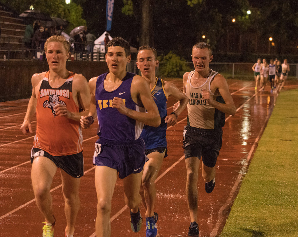 Athlete prepares for pole vault on a track with others watching.