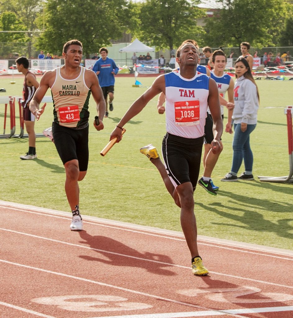 Athlete prepares for pole vault on a track with others watching.