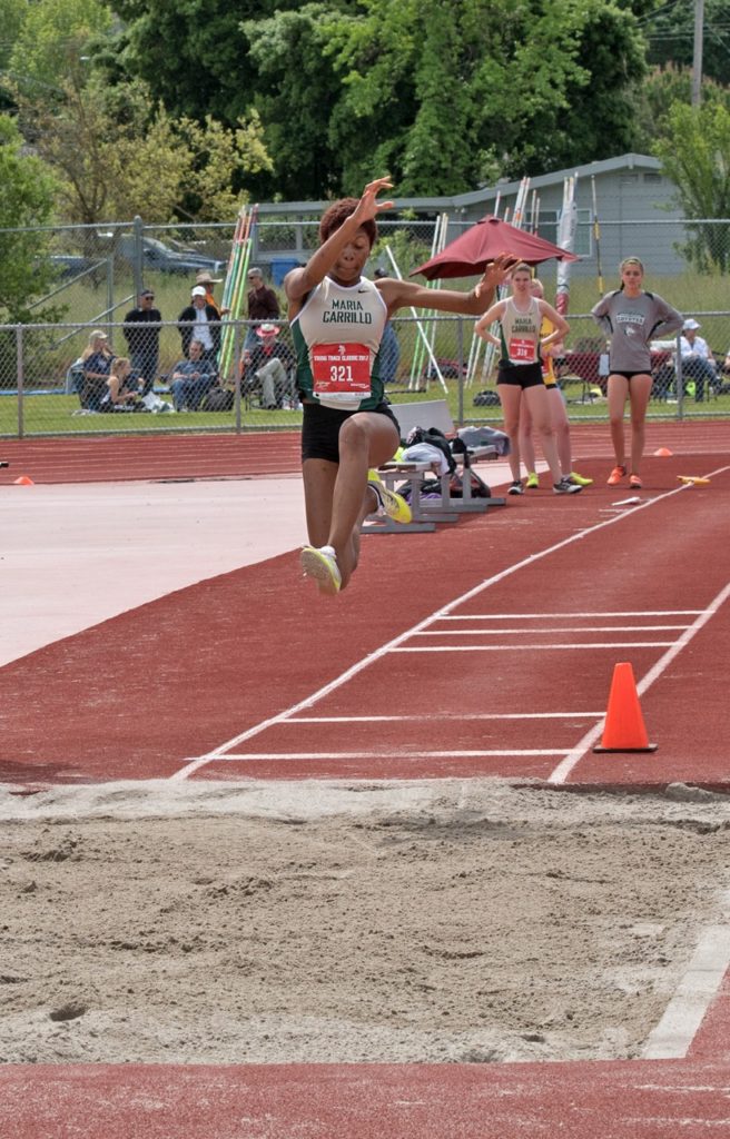 Athlete prepares for pole vault on a track with others watching.
