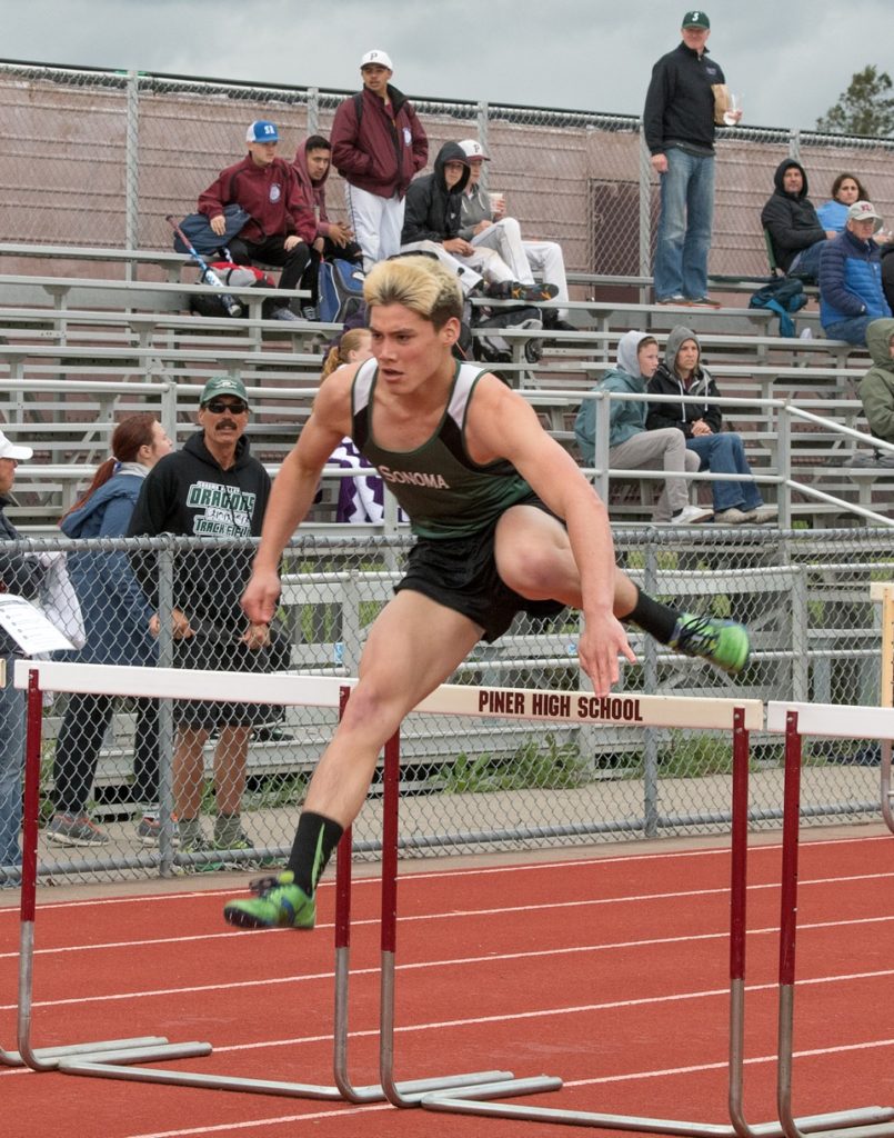 Athlete prepares for pole vault on a track with others watching.