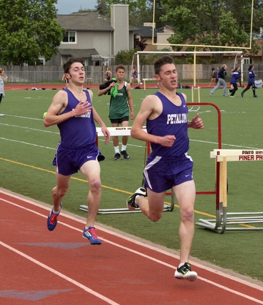 Athlete prepares for pole vault on a track with others watching.