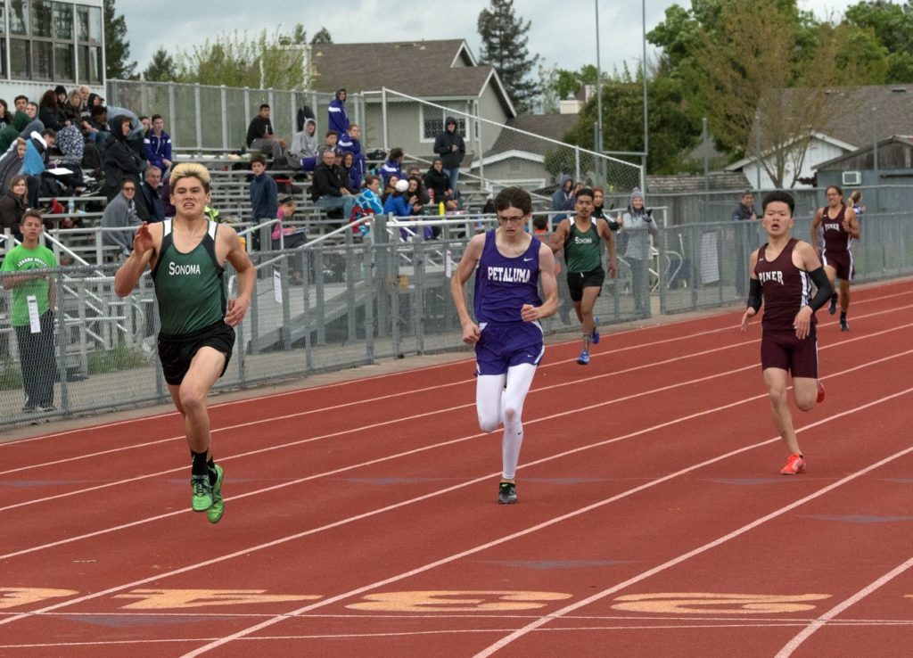 Athlete prepares for pole vault on a track with others watching.