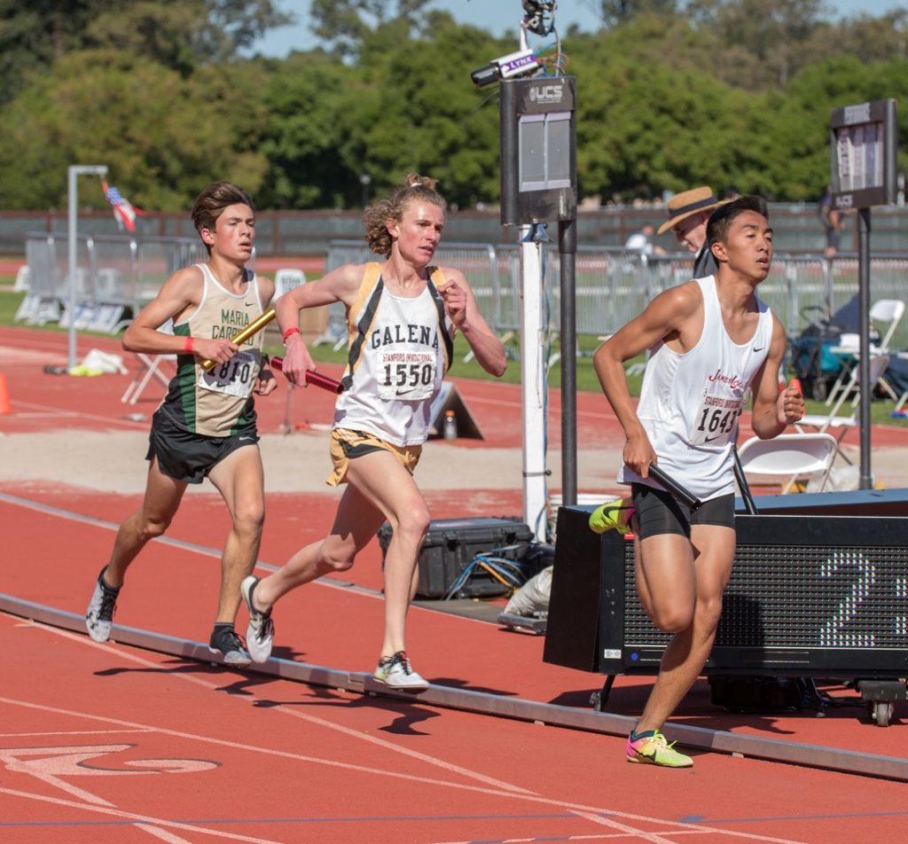 Athlete prepares for pole vault on a track with others watching.