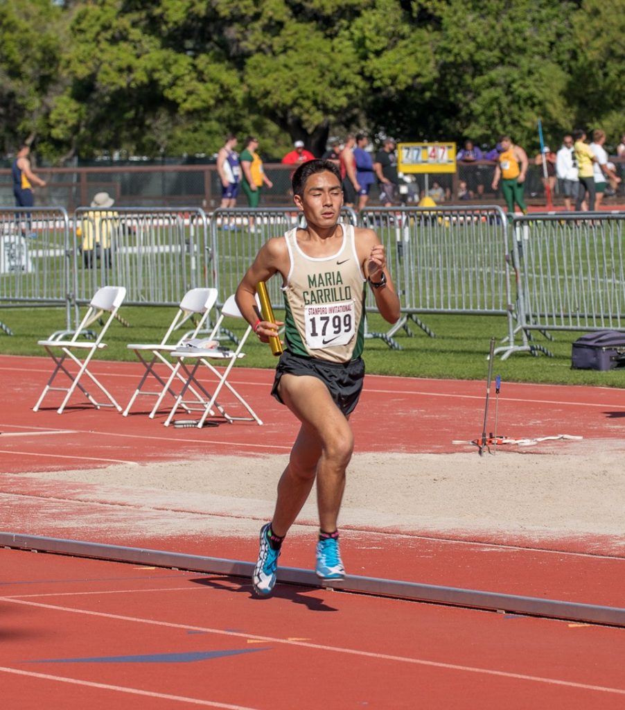 Athlete prepares for pole vault on a track with others watching.