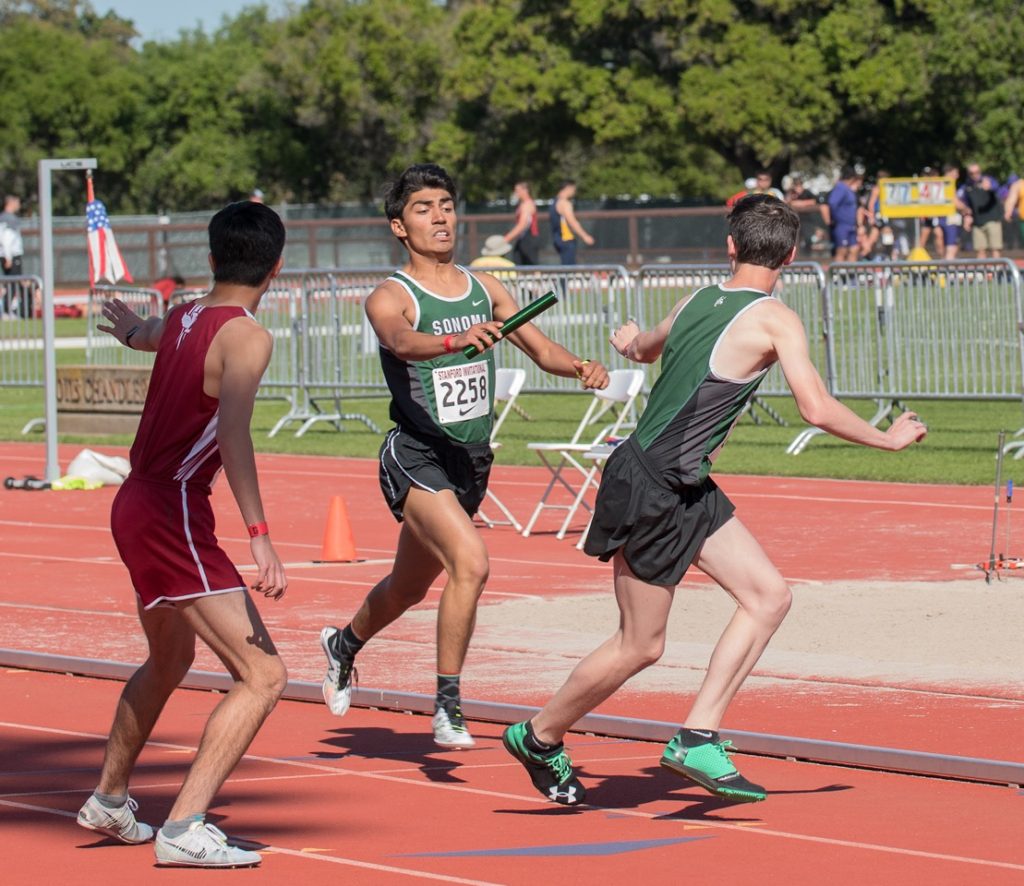 Athlete prepares for pole vault on a track with others watching.