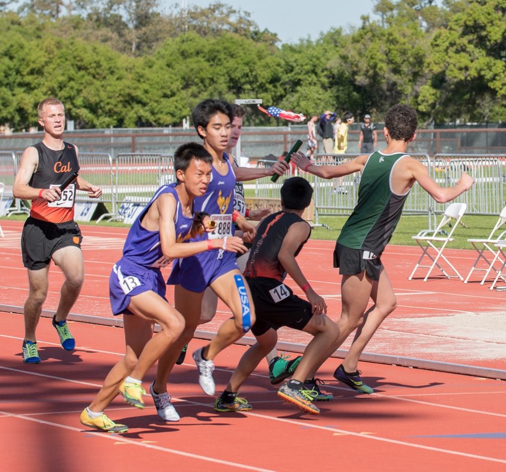 Athlete prepares for pole vault on a track with others watching.