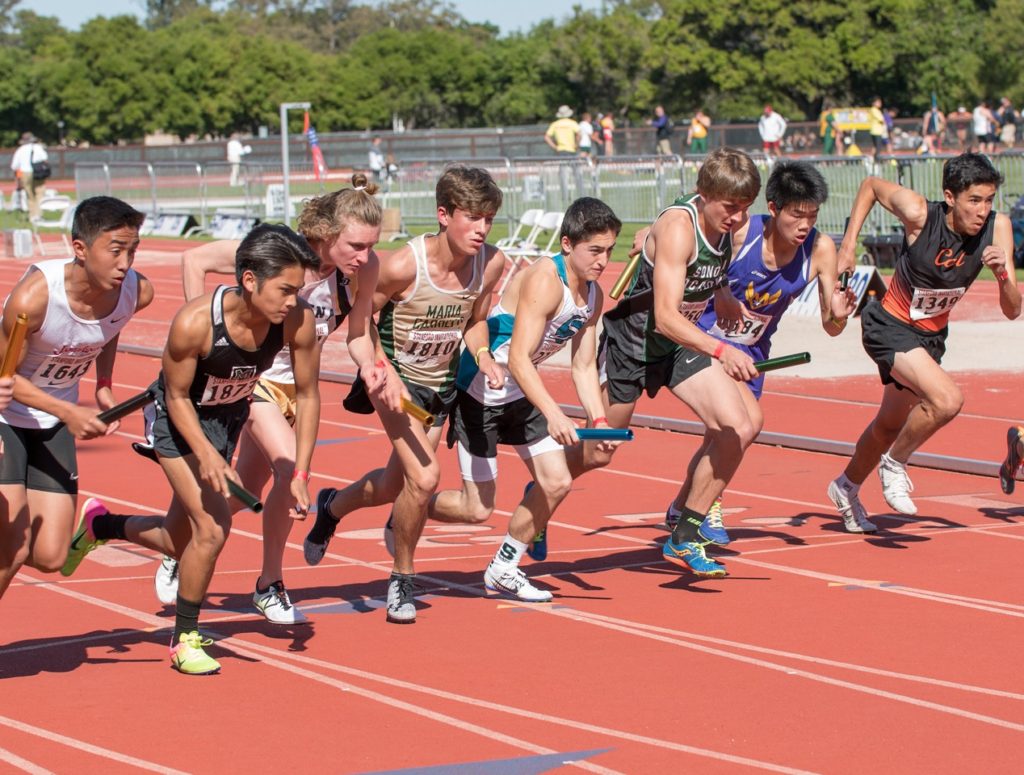 Athlete prepares for pole vault on a track with others watching.