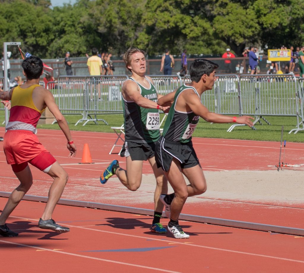 Athlete prepares for pole vault on a track with others watching.