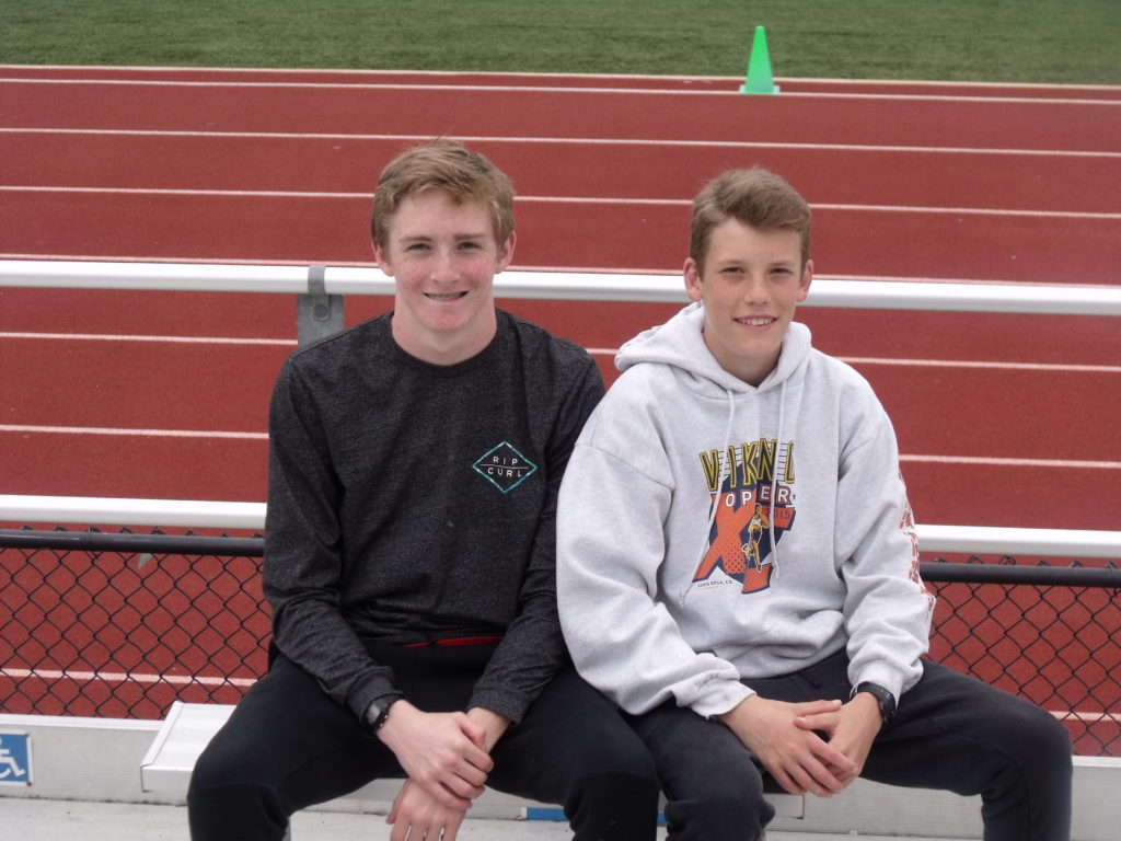 Athlete prepares for pole vault on a track with others watching.