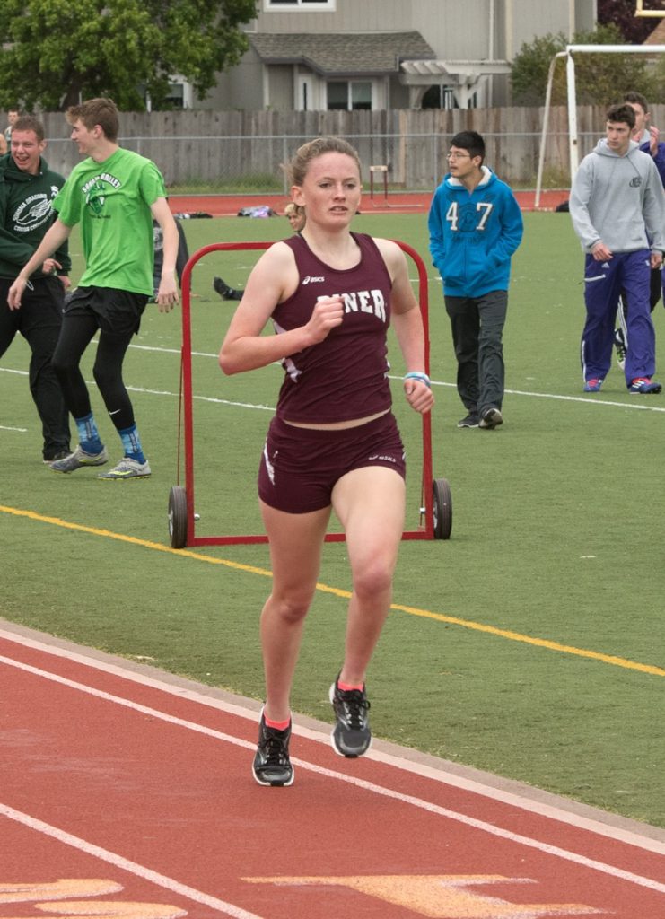Athlete prepares for pole vault on a track with others watching.