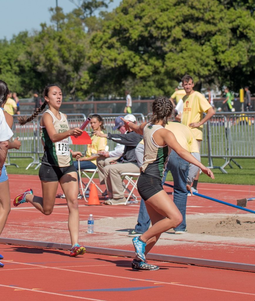 Athlete prepares for pole vault on a track with others watching.