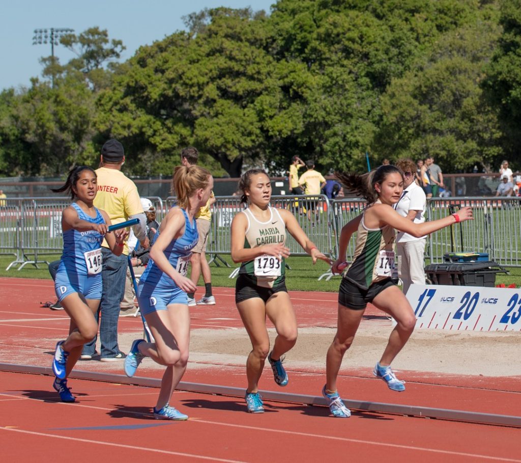Athlete prepares for pole vault on a track with others watching.