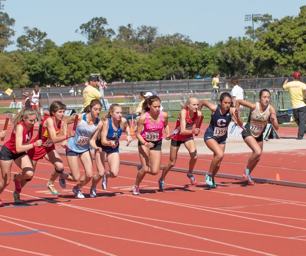 Athlete prepares for pole vault on a track with others watching.