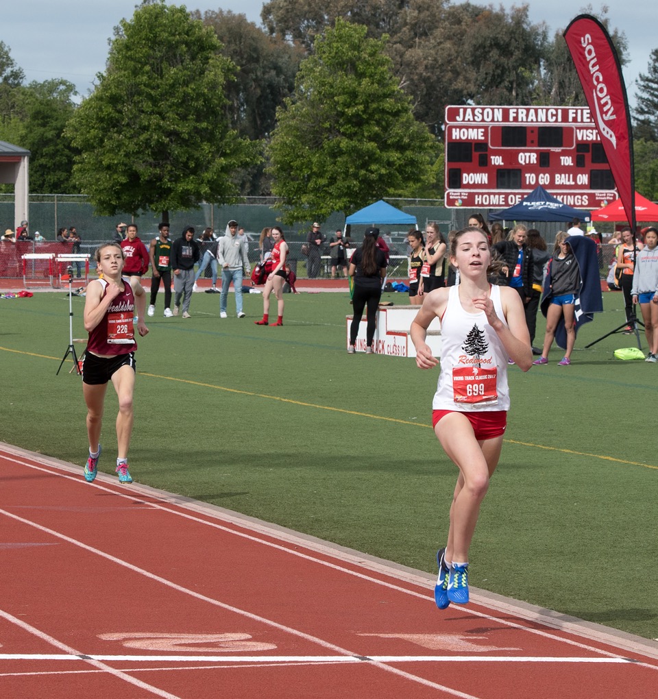 Athlete prepares for pole vault on a track with others watching.