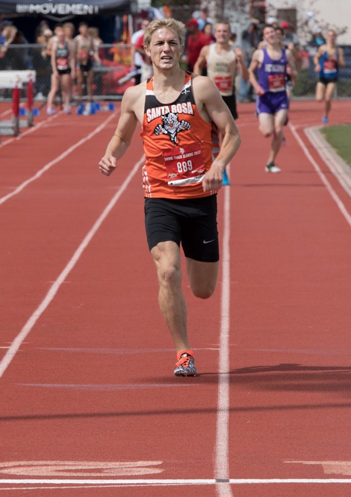 Athlete prepares for pole vault on a track with others watching.