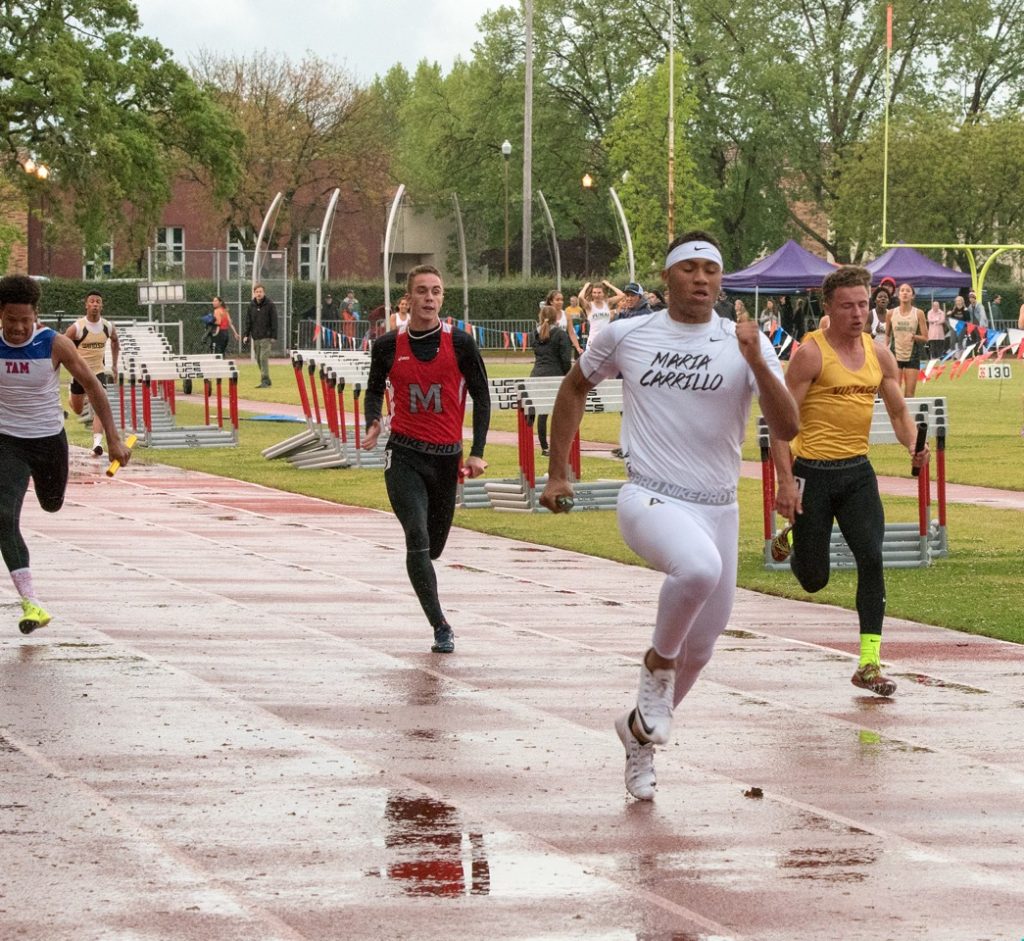 Athlete prepares for pole vault on a track with others watching.