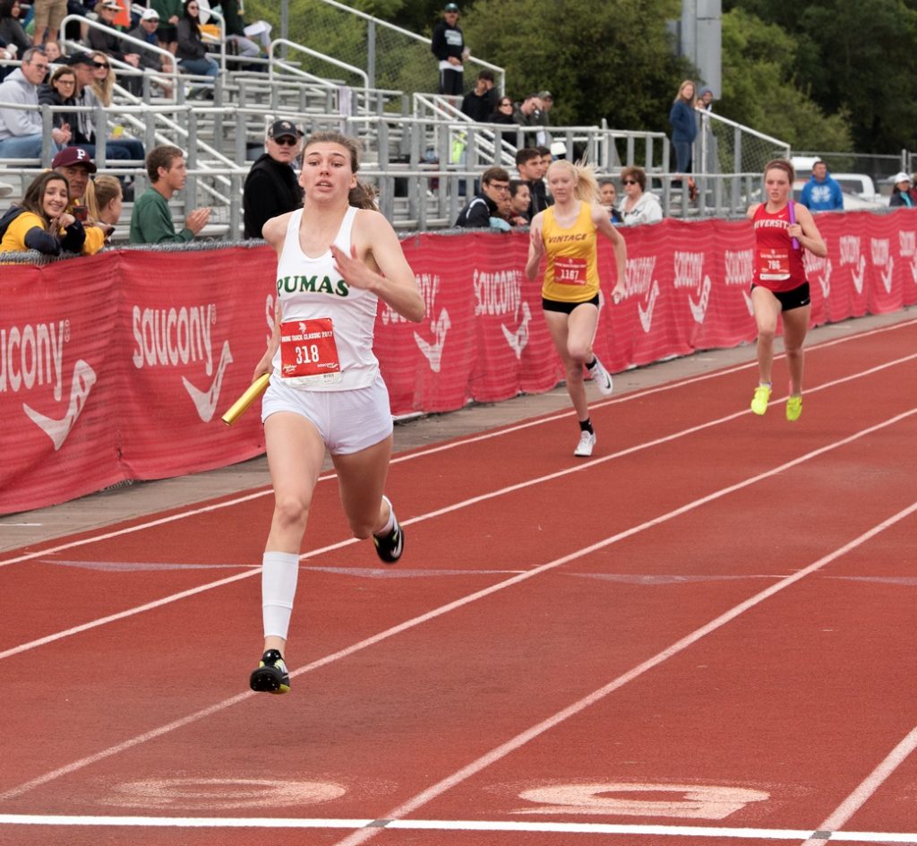 Athlete prepares for pole vault on a track with others watching.