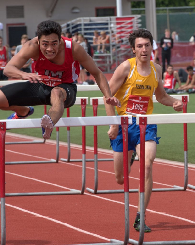 Athlete prepares for pole vault on a track with others watching.
