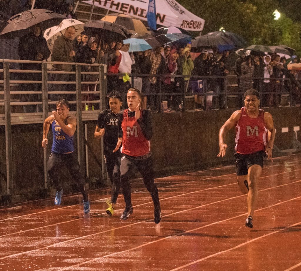 Athlete prepares for pole vault on a track with others watching.