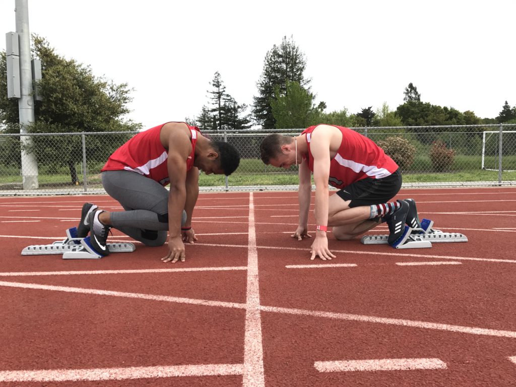Athlete prepares for pole vault on a track with others watching.