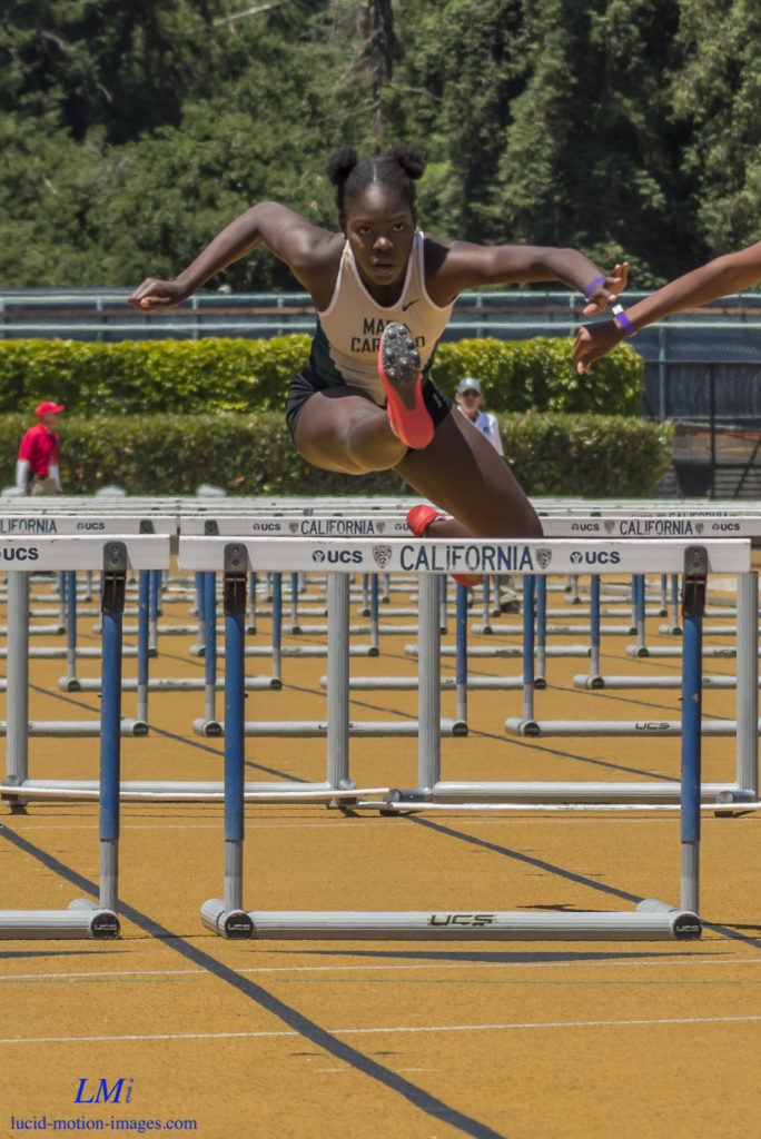 Athlete prepares for pole vault on a track with others watching.