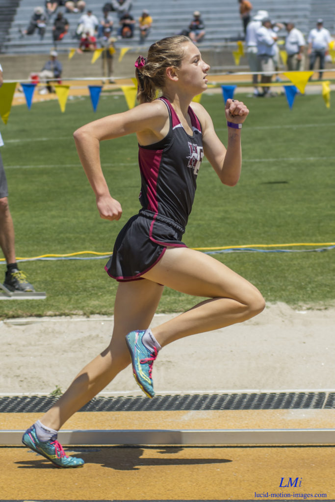 Athlete prepares for pole vault on a track with others watching.