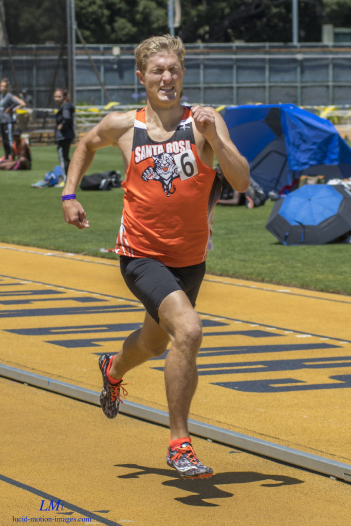 Athlete prepares for pole vault on a track with others watching.