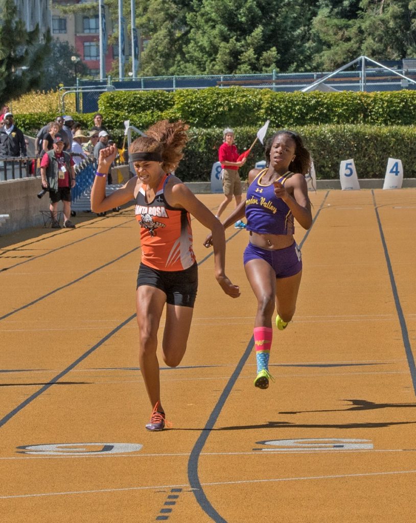 Athlete prepares for pole vault on a track with others watching.