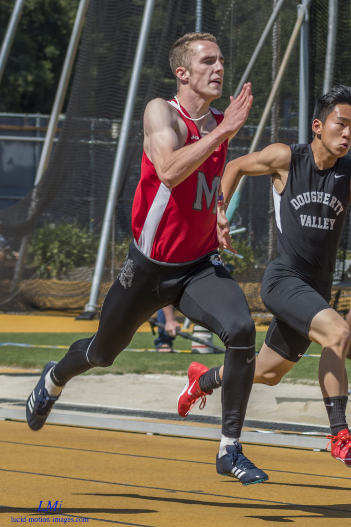 Athlete prepares for pole vault on a track with others watching.