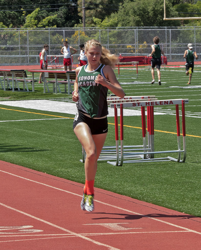 Athlete prepares for pole vault on a track with others watching.
