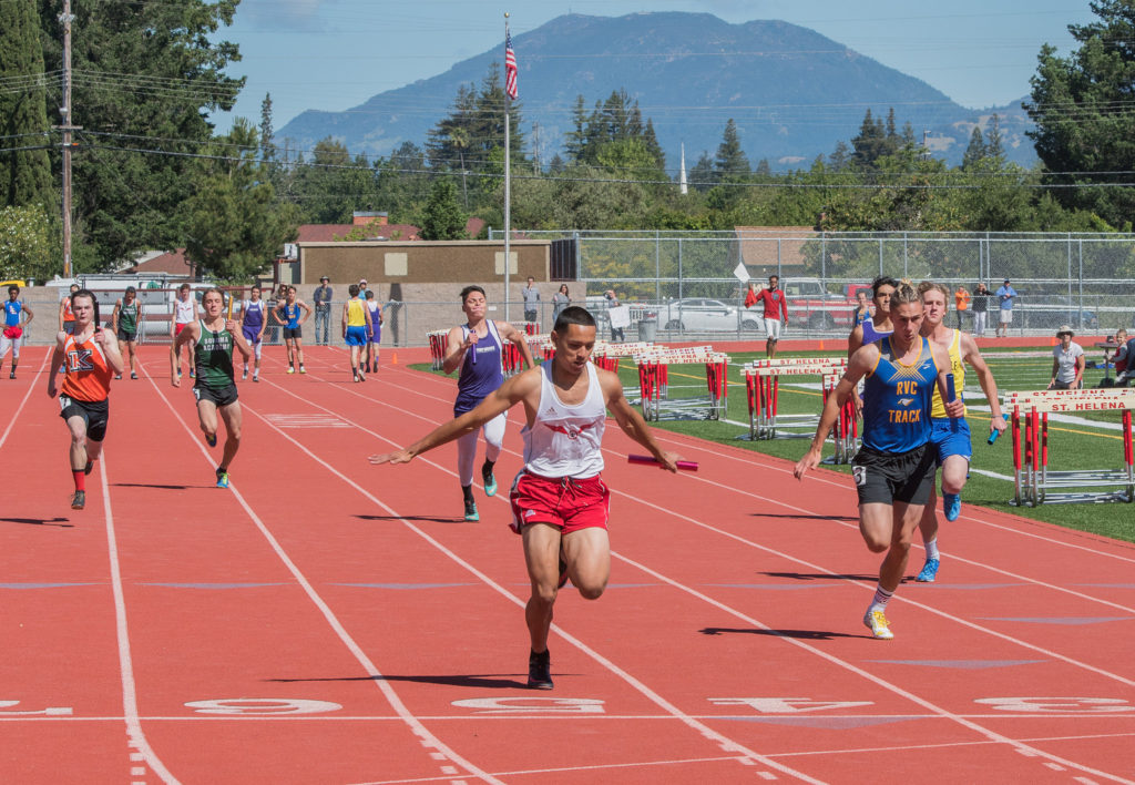 Athlete prepares for pole vault on a track with others watching.