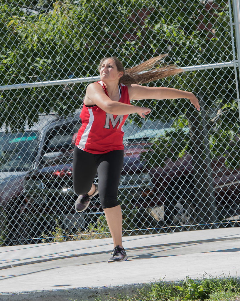 Athlete prepares for pole vault on a track with others watching.