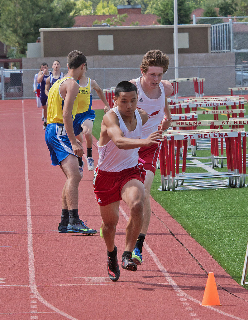 Athlete prepares for pole vault on a track with others watching.