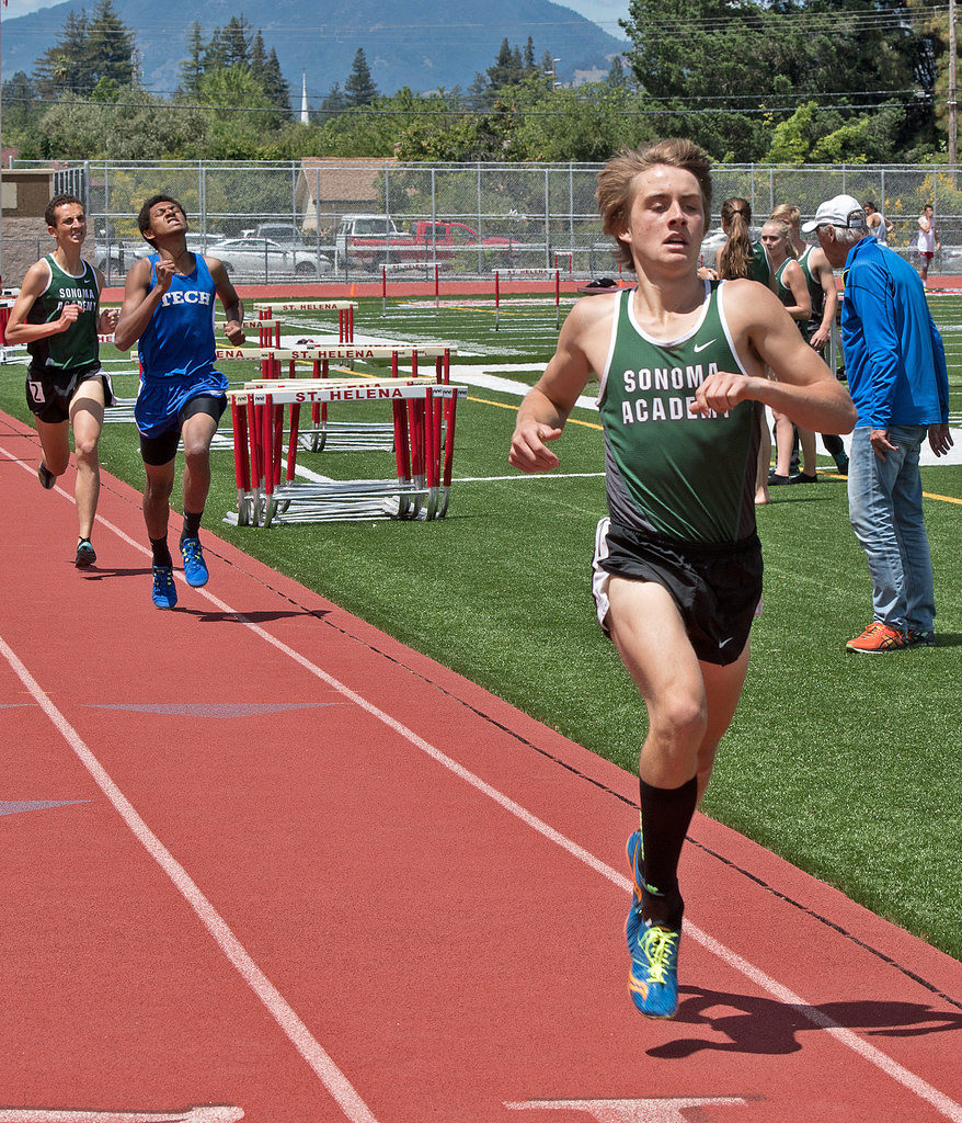 Athlete prepares for pole vault on a track with others watching.