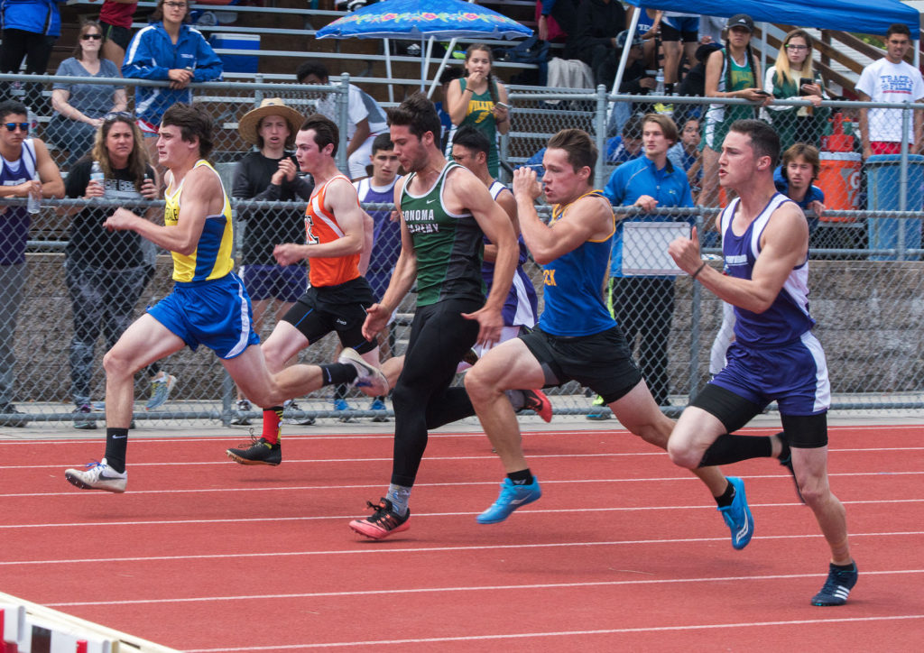 Athlete prepares for pole vault on a track with others watching.