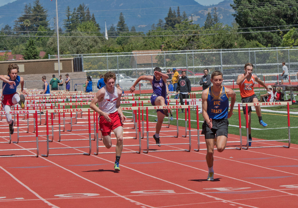 Athlete prepares for pole vault on a track with others watching.