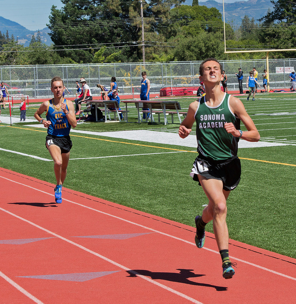 Athlete prepares for pole vault on a track with others watching.