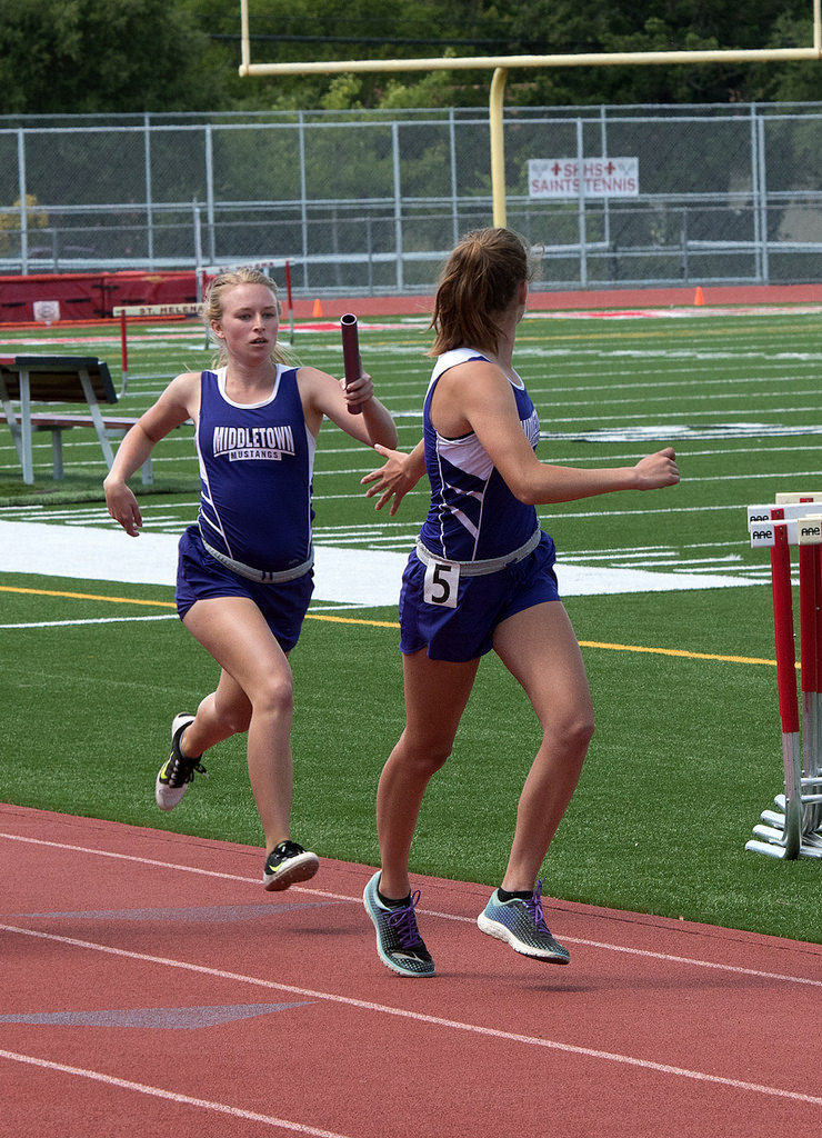 Athlete prepares for pole vault on a track with others watching.