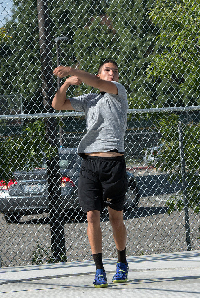 Athlete prepares for pole vault on a track with others watching.