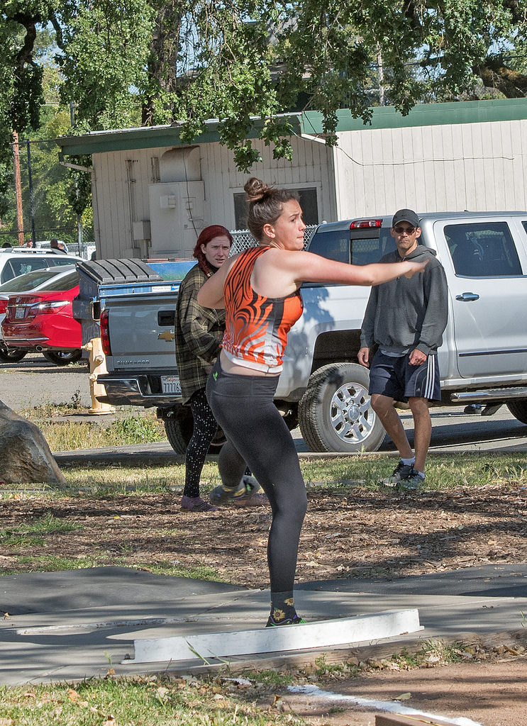 Athlete prepares for pole vault on a track with others watching.
