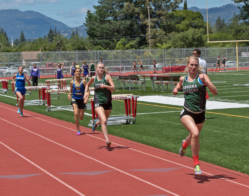 Athlete prepares for pole vault on a track with others watching.