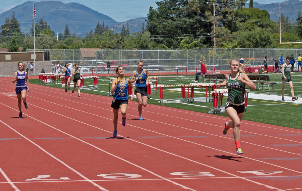 Athlete prepares for pole vault on a track with others watching.