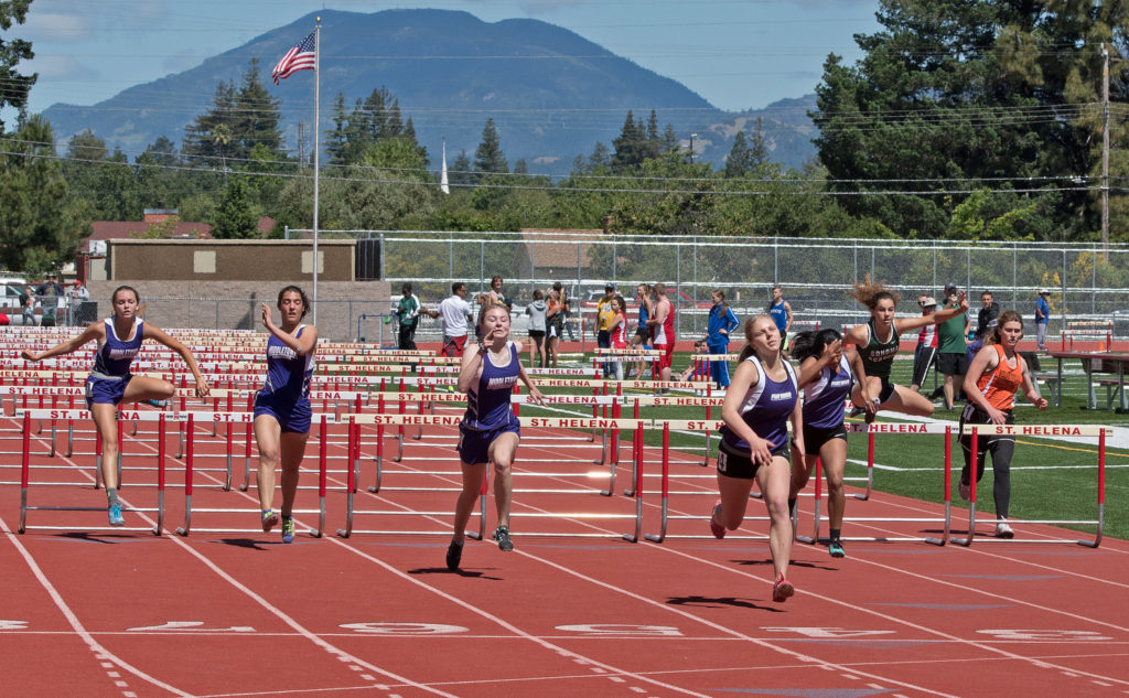 Athlete prepares for pole vault on a track with others watching.