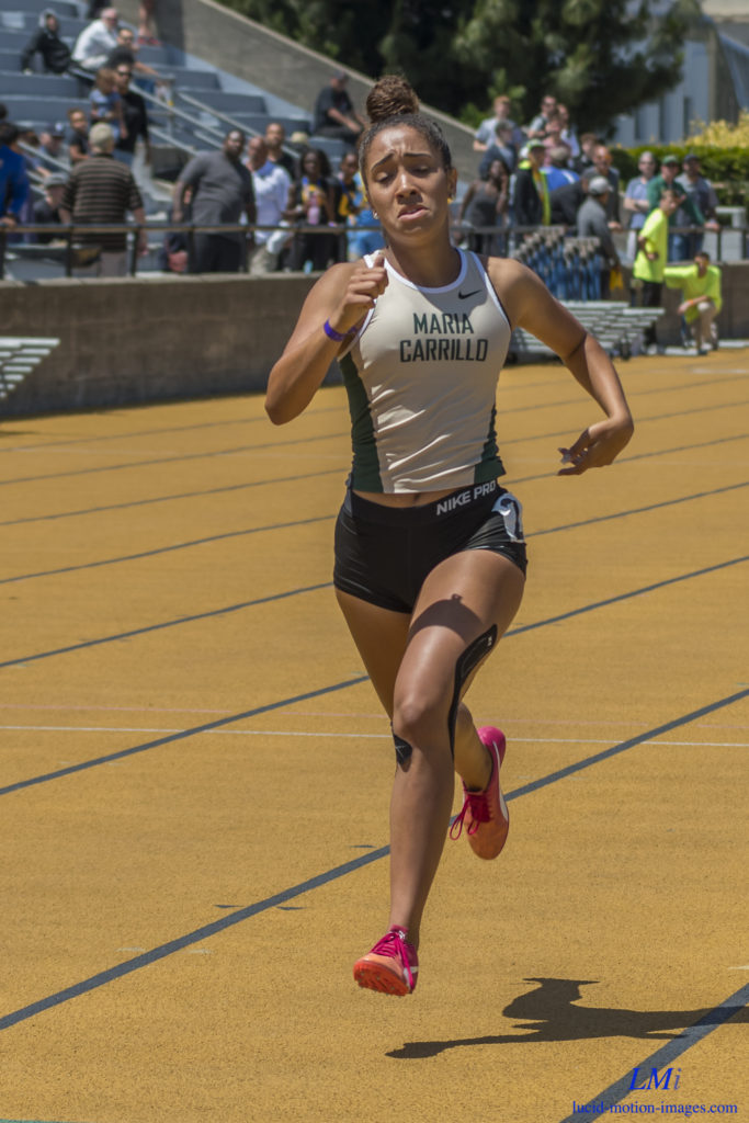Athlete prepares for pole vault on a track with others watching.