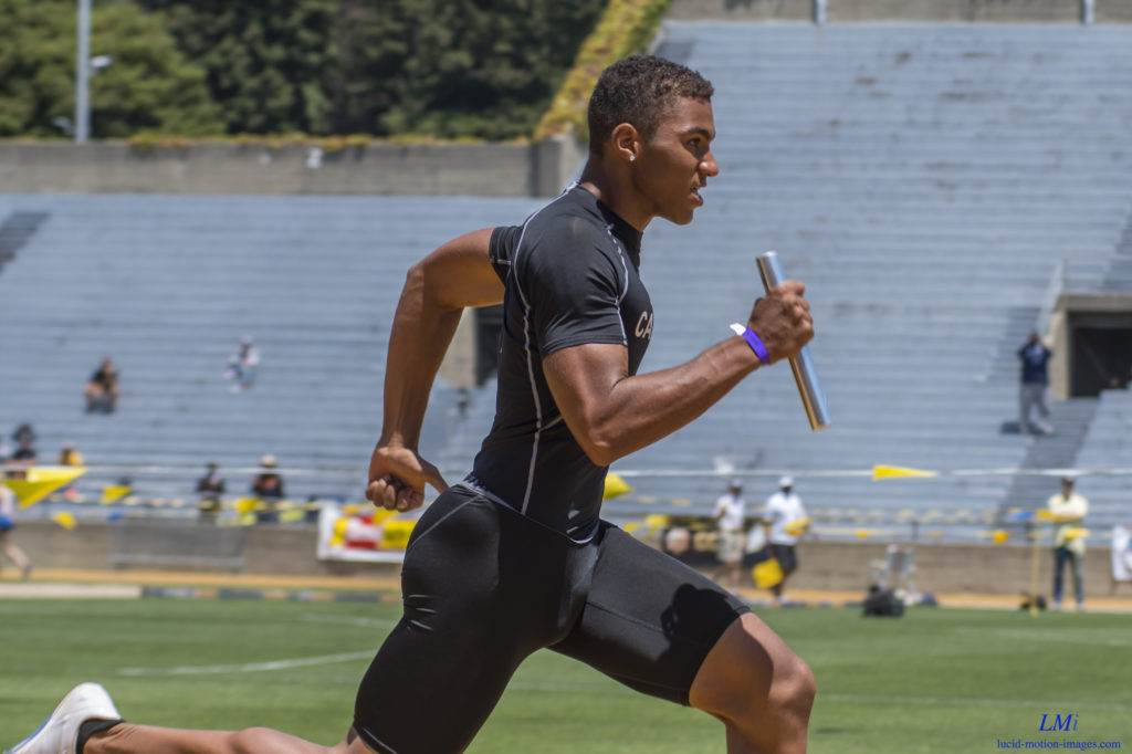 Athlete prepares for pole vault on a track with others watching.