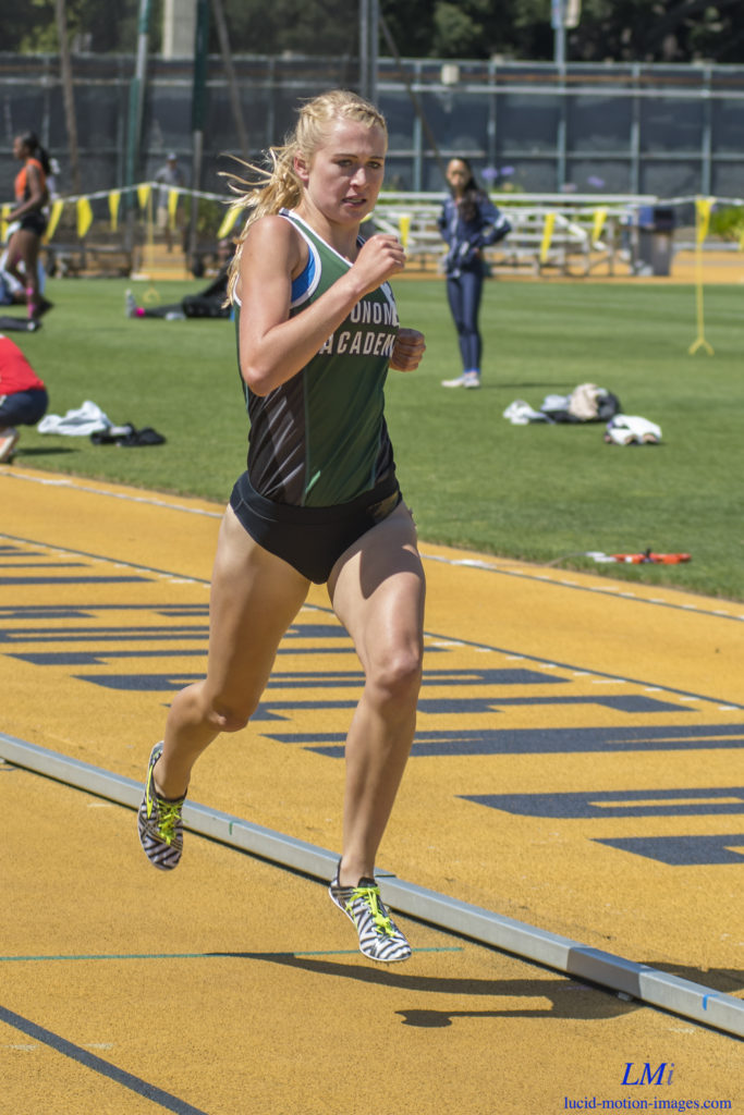 Athlete prepares for pole vault on a track with others watching.