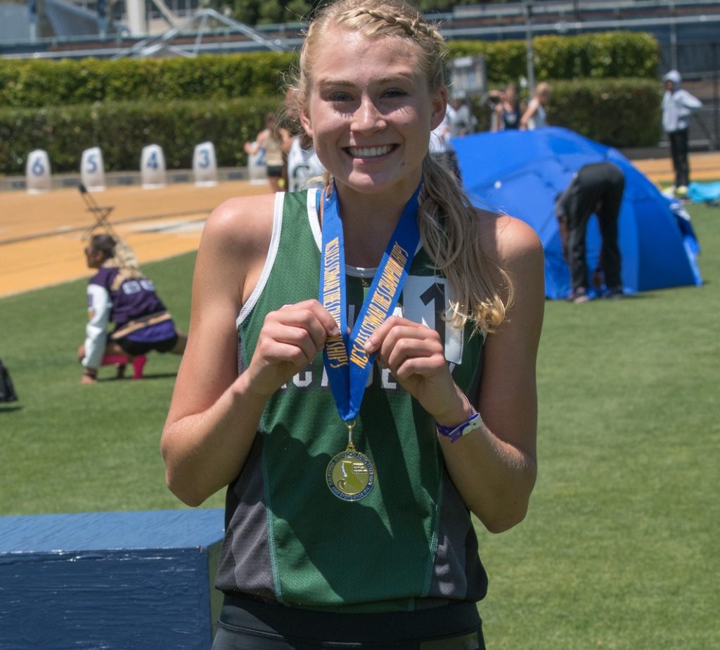 Athlete prepares for pole vault on a track with others watching.
