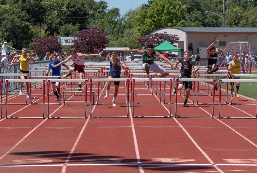 Athlete prepares for pole vault on a track with others watching.