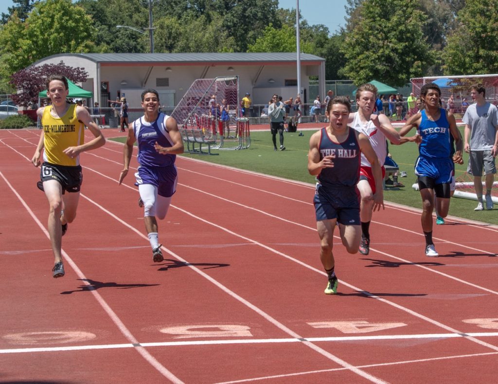 Athlete prepares for pole vault on a track with others watching.