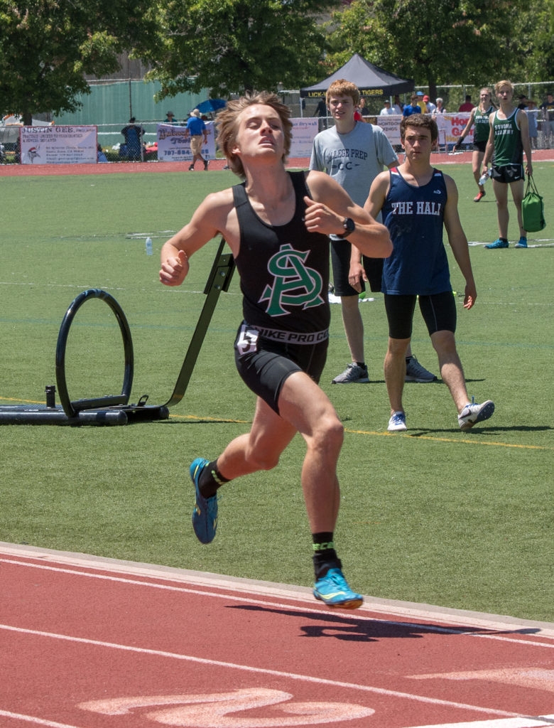 Athlete prepares for pole vault on a track with others watching.